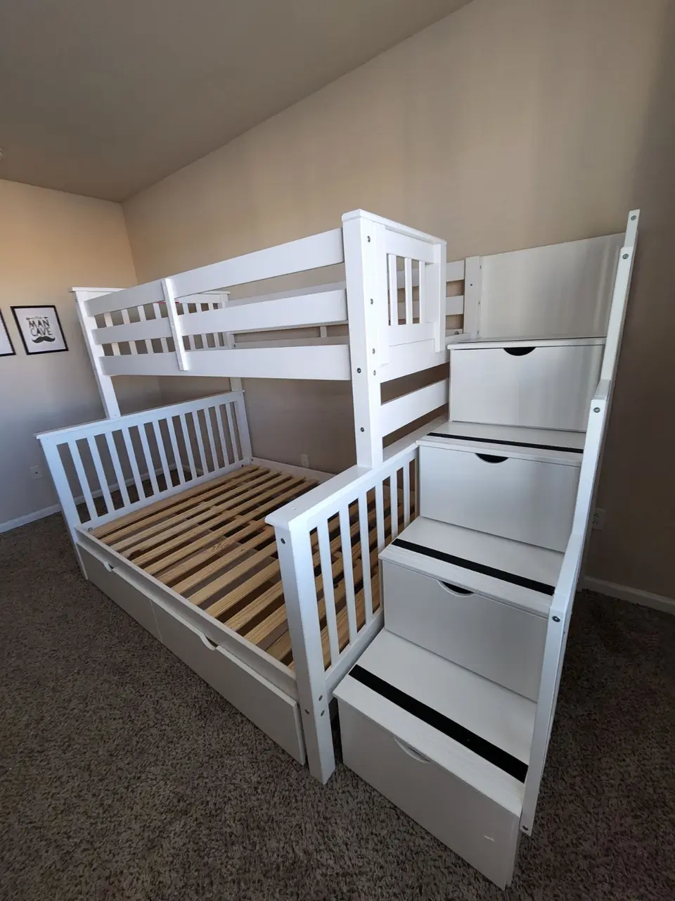 White twin-over-full bunk bed with storage stairs, assembled in a child's room