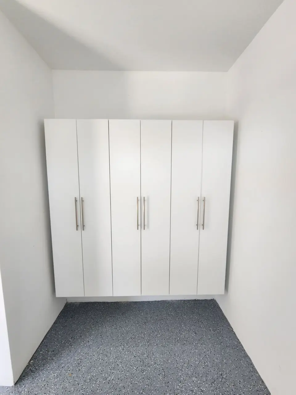 Tall white cabinet closet system installed in an alcove