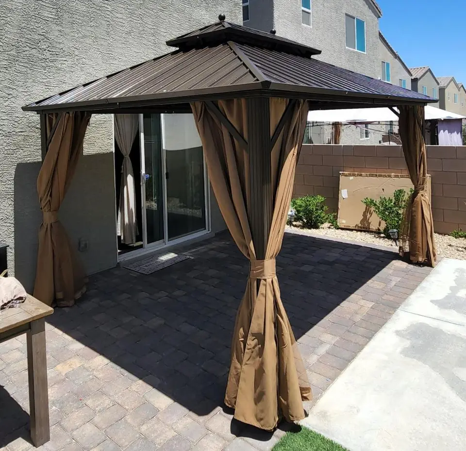 Brown hardtop gazebo with curtains on a paver patio