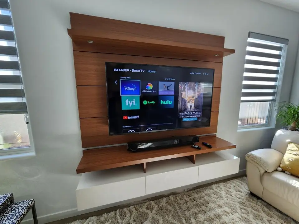 Wall-mounted TV on a walnut media panel above a floating white console